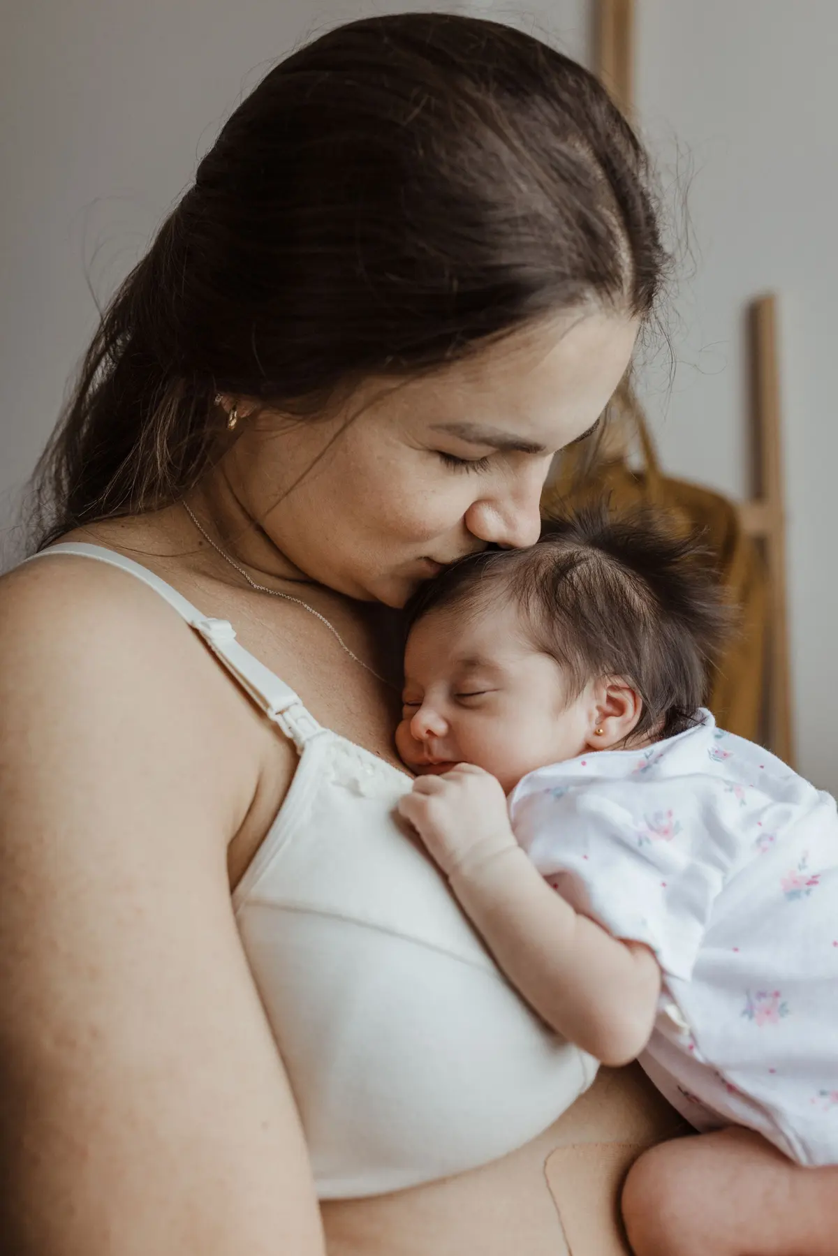 Una mamá besa la cabeza de su bebé dormido